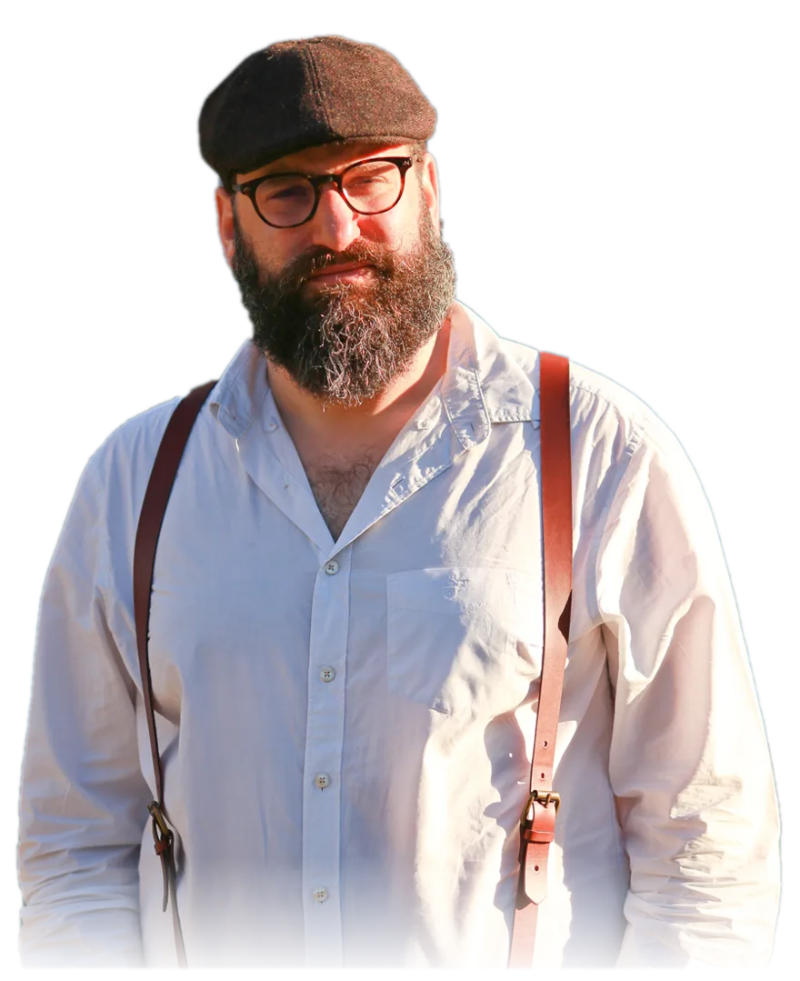 Jonathan Shubs, standing outdoors in warm light, wearing a cap and a white shirt